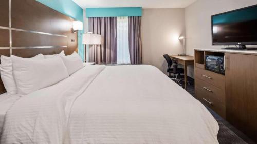 a hotel room with a large white bed and a desk at Best Western Galt Inn in Galt