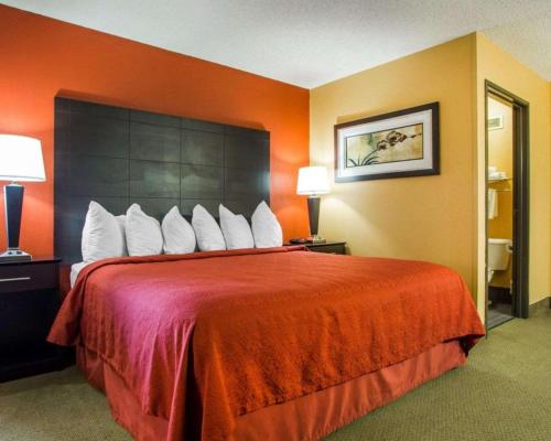 a hotel room with a large bed with red sheets at Quality Inn & Suites Kimberly - Appleton East in Kimberly