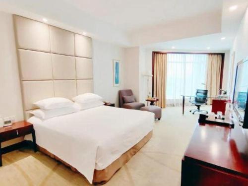 a bedroom with a large white bed and a chair at New Century Grand Hotel Zhuji Yaojiang in Shaoxing