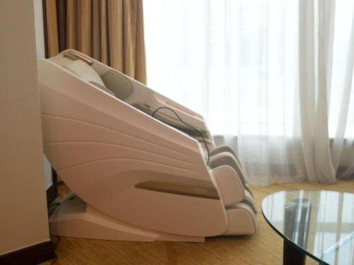 a white couch in a room with a glass table at New Century Grand Hotel Zhuji Yaojiang in Shaoxing