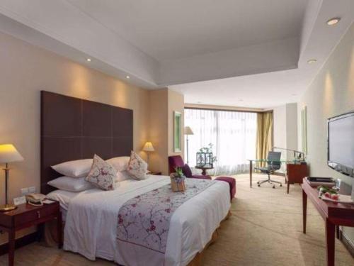 a hotel room with a large bed and a television at New Century Grand Hotel Zhuji Yaojiang in Shaoxing