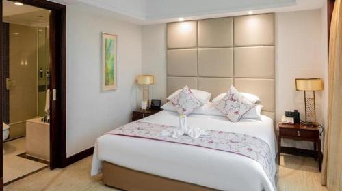 a bedroom with a large white bed with a large headboard at New Century Grand Hotel Zhuji Yaojiang in Shaoxing