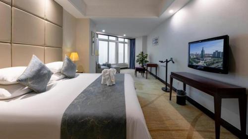 a bedroom with a large bed and a flat screen tv at New Century Grand Hotel Zhuji Yaojiang in Shaoxing