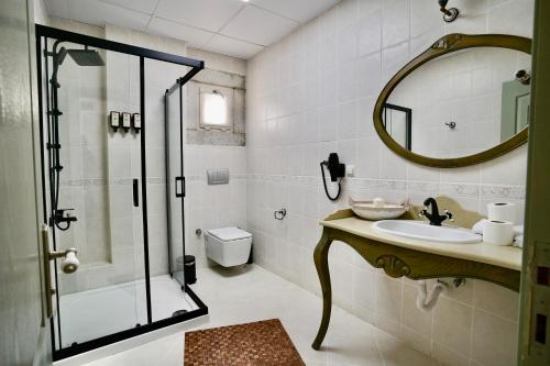 a bathroom with a sink and a shower with a mirror at Cumbalıca Flora in Cesme
