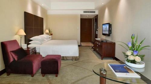 a hotel room with a bed and a couch and a table at New Century Grand Hotel Zhuji Yaojiang in Shaoxing