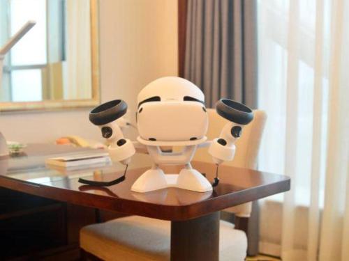 a white robot sitting on a desk in a room at New Century Grand Hotel Zhuji Yaojiang in Shaoxing
