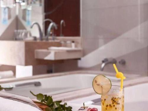 a bathroom with a tub and a drink with a spoon at New Century Grand Hotel Zhuji Yaojiang in Shaoxing