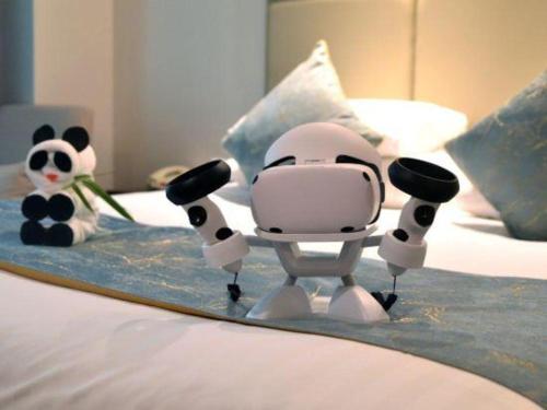 a toy robot on a bed with a stuffed panda bear at New Century Grand Hotel Zhuji Yaojiang in Shaoxing