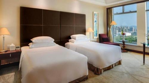 two beds in a hotel room with a large window at New Century Grand Hotel Zhuji Yaojiang in Shaoxing