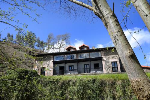 a house on a hill with a tree at Apartamentos Santa Lucia in Cabezón de la Sal