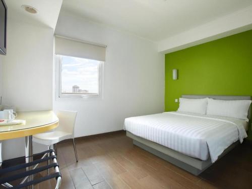 een slaapkamer met een wit bed en een groene muur bij Amaris Hotel La Codefin Kemang in Jakarta