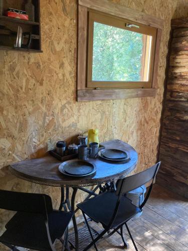 - une table dans une pièce avec 2 chaises et une fenêtre dans l'établissement Le Cabanon d 'Aix, à Aix-en-Provence