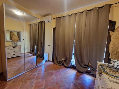 a bedroom with a mirror and a dresser and curtains at Villa Colle degli Ulivi con piscina e sguardo sul mare in Cerveteri