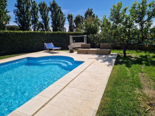 a swimming pool in a yard with a blue chair and a chair at Villa Colle degli Ulivi con piscina e sguardo sul mare in Cerveteri