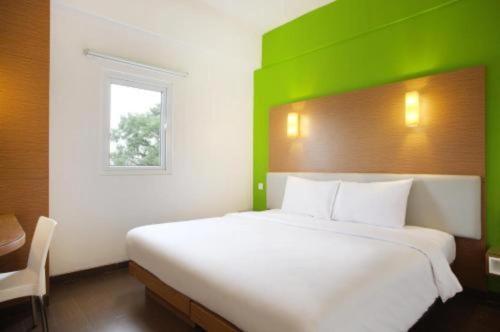 a bedroom with a large white bed with a green headboard at Amaris Hotel Pakuan Bogor in Bogor