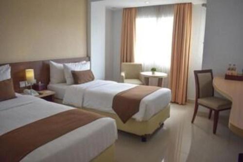 a hotel room with two beds and a desk at Bogor Valley Hotel in Bogor