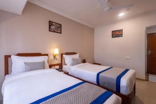 a hotel room with two beds and a window at Hotel Pravasa Stay in Vadodara