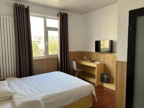 ein Schlafzimmer mit einem Bett, einem Schreibtisch und einem Fernseher in der Unterkunft 7 Days Inn Tianjin Zhongshan Road North Station in Tianjin