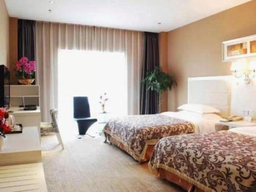 a hotel room with two beds and a desk and a window at Chengdu Huadu Times Hotel in Chengdu