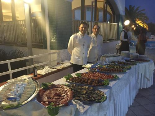 two chefs standing in front of a buffet of food at Hotel Poseidon in Diamante