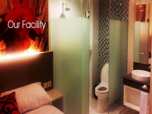 ein Badezimmer mit einem Badezimmer mit einem Feuer in der Wand in der Unterkunft Clay Hotel Jakarta in Jakarta