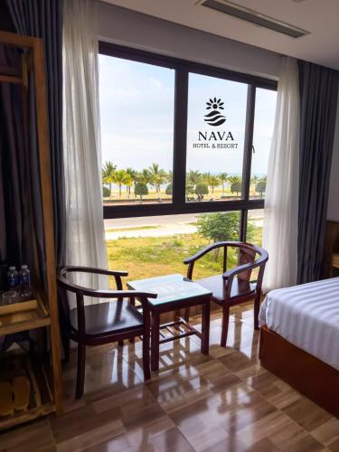 a bedroom with a bed and two chairs and a window at Nava Hotel & Resort in Dong Hoi