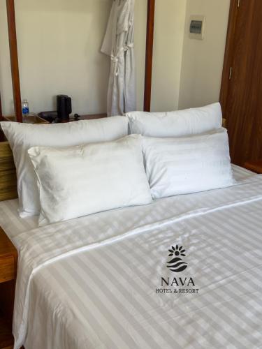 a bed with white sheets and pillows in a room at Nava Hotel & Resort in Dong Hoi