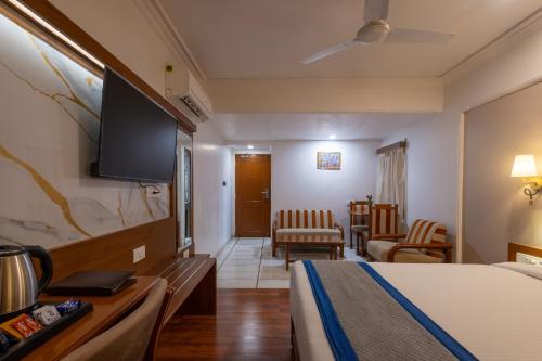 a hotel room with a bed and a flat screen tv at Hotel Pravasa Stay in Vadodara