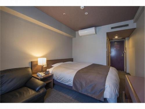 a hotel room with a bed and a couch at Hadano Yugawara Onsen Manyo no Yu in Hadano