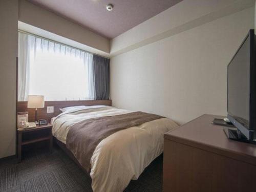 a bedroom with a bed and a flat screen tv at Hadano Yugawara Onsen Manyo no Yu in Hadano