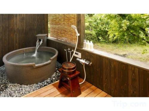 a bath tub with a faucet and a window at Kyoto Keburikawa Hotel in Kameoka