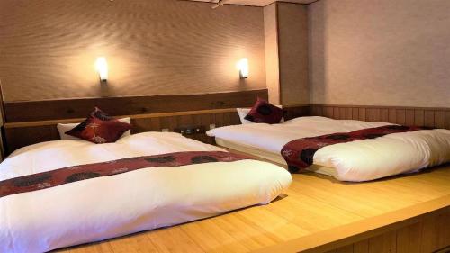 two beds in a hotel room with lights on the wall at Hotel Miyama in Chichibu