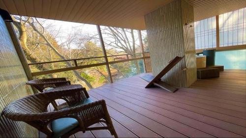 a balcony with two wicker chairs on a wooden deck at Hotel Miyama in Chichibu
