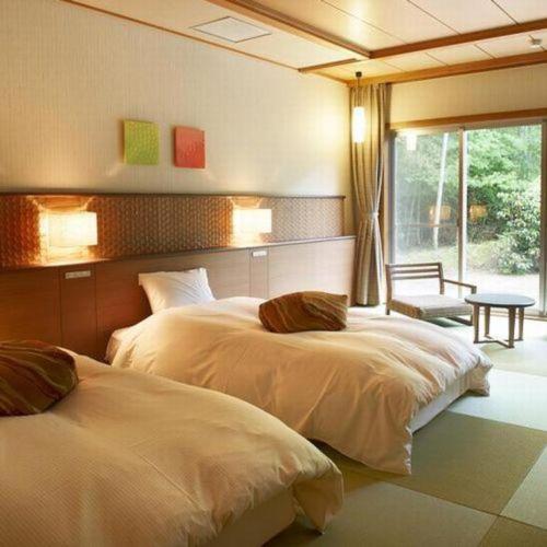 a bedroom with two beds and a window at Kyoto Keburikawa Hotel in Kameoka