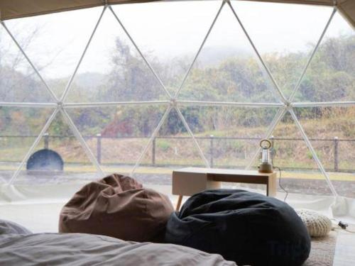 a person laying on a bed in front of a window at Kyoto Keburikawa Hotel in Kameoka