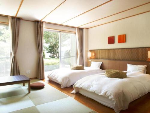 a bedroom with two beds and a large window at Kyoto Keburikawa Hotel in Kameoka