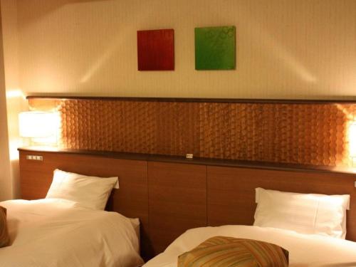 two beds in a hotel room with paintings on the wall at Kyoto Keburikawa Hotel in Kameoka