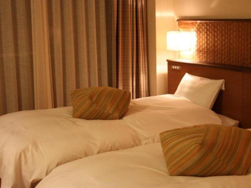 two beds in a hotel room with white sheets at Kyoto Keburikawa Hotel in Kameoka