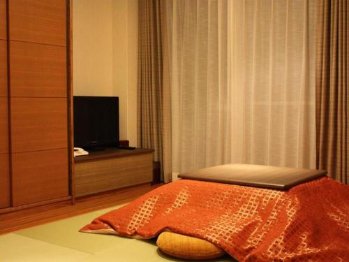 a bedroom with a bed and a flat screen tv at Kyoto Keburikawa Hotel in Kameoka