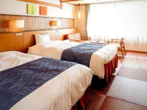 a hotel room with three beds and a window at Kyoto Keburikawa Hotel in Kameoka