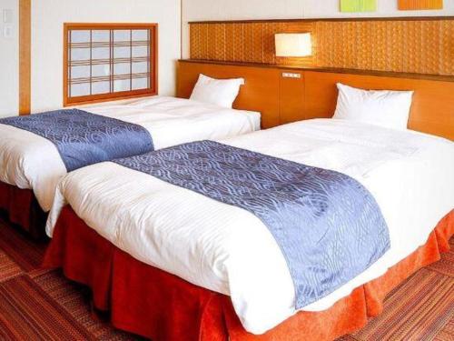 two beds in a hotel room next to each other at Kyoto Keburikawa Hotel in Kameoka