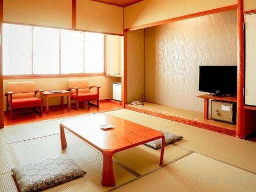 a living room with a coffee table and a tv at Kyoto Keburikawa Hotel in Kameoka