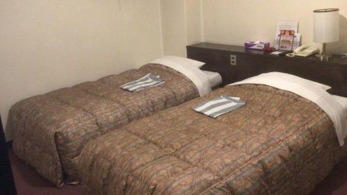 two beds sitting next to each other in a hotel room at HotelNewYama in Yamanouchi