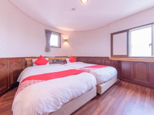 a bedroom with two beds with red pillows at Tabist Hotel Sankoen in Hitachi