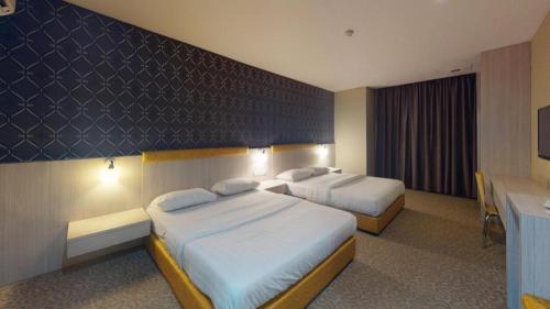 a hotel room with two beds and a desk at Clover Hotel in Johor Bahru