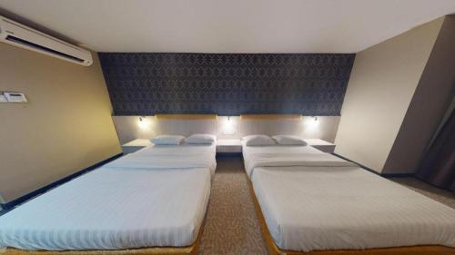 a room with three beds in it with lights at Clover Hotel in Johor Bahru
