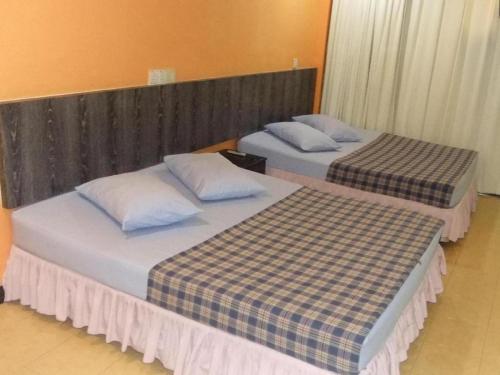 two beds sitting next to each other in a room at Hotel Lavender in Alor Setar