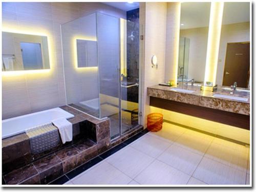 a bathroom with a shower and a tub and a sink at Hotel AIFA in Labuan