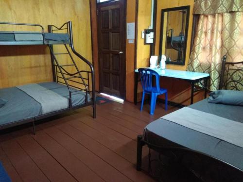 a room with two bunk beds and a table and a desk at MyDesaStay in Sekincan