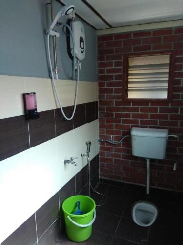 a bathroom with a shower and a green bucket at MyDesaStay in Sekincan